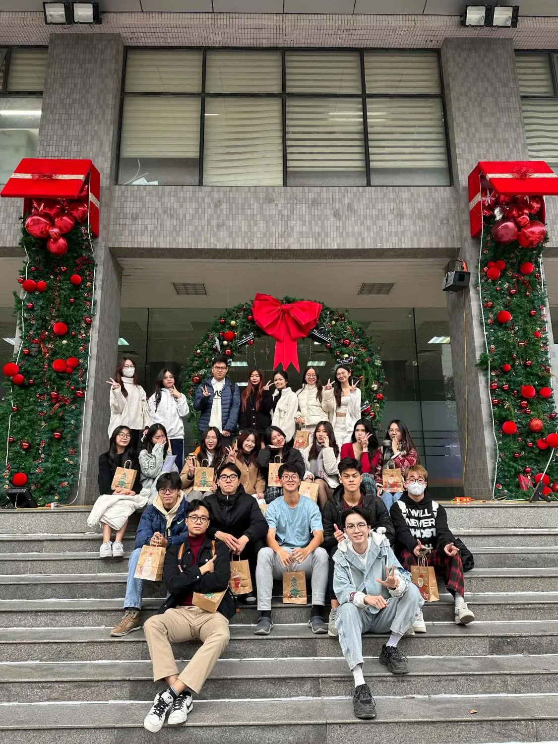 The department on the Christmas-decorated steps, gift bags in hand