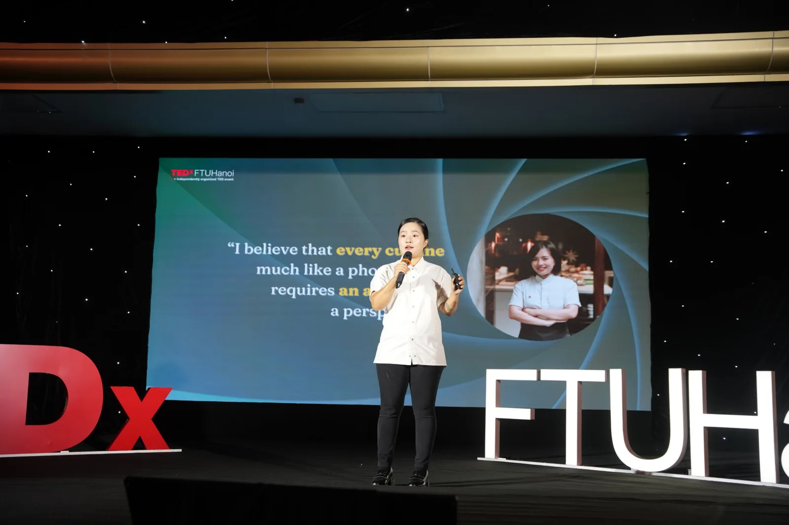 Sam Trần on stage, the aperture motif behind her