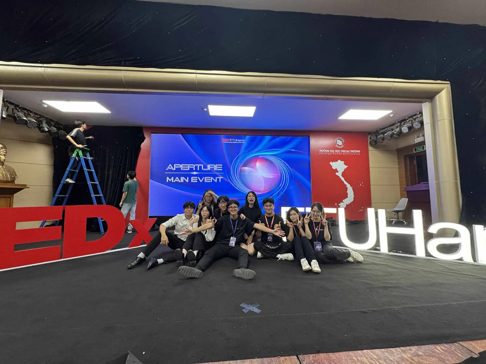 The full core team on the main-event stage, in front of the TEDx FTUHanoi letters